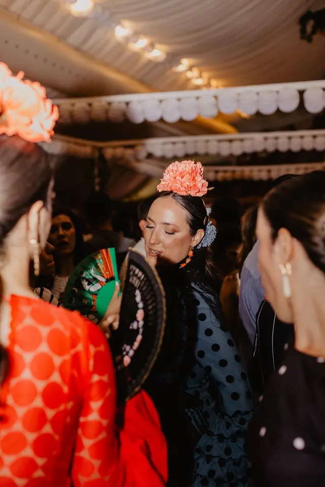 Mujeres con trajes de flamenca y flores en el pelo bajo la carpa