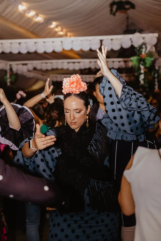 Mujer bailando con mantón bajo los farolillos blancos