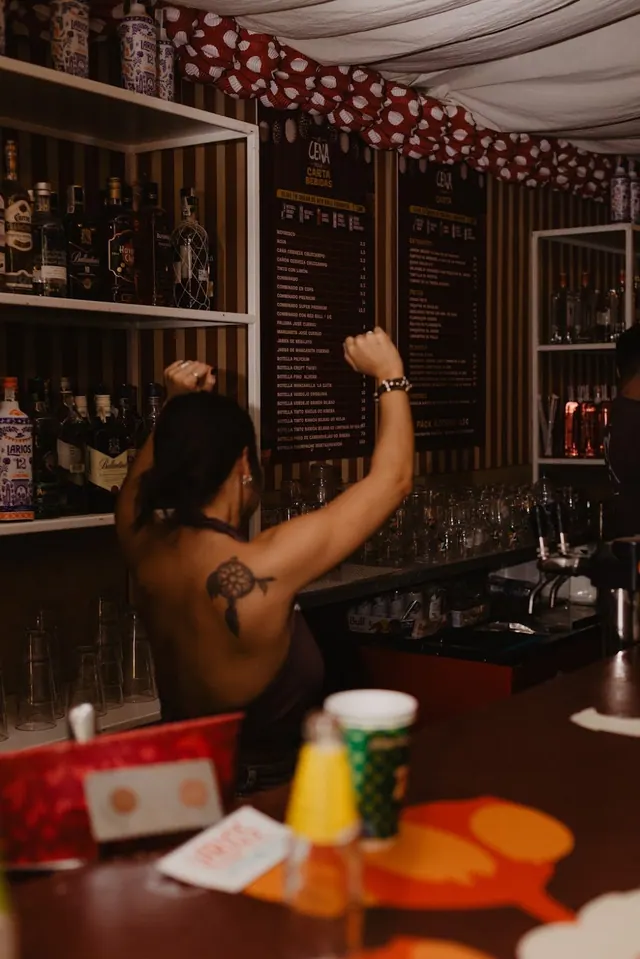 Barra de La Cena con la carta de bebidas al fondo y la carpa de farolillos