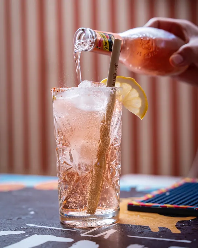 Copa con hielo, limón y una cañita mientras se sirve un refresco