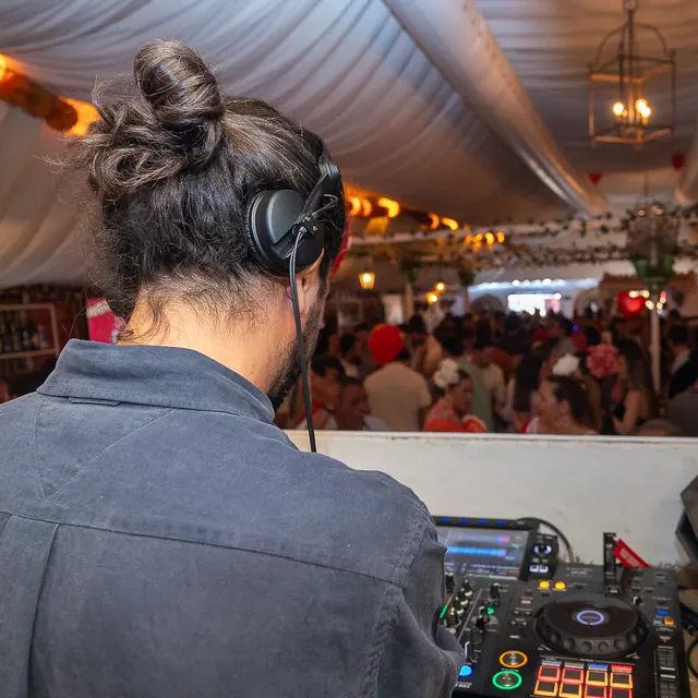 DJ en la cabina con la carpa llena delante