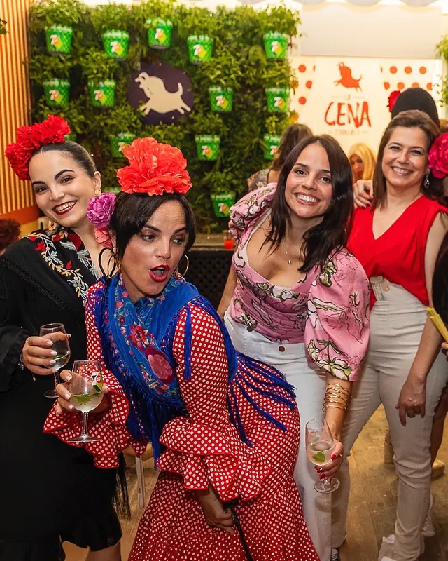 Amigas con trajes de flamenca posando ante el muro verde con el toro de La Cena