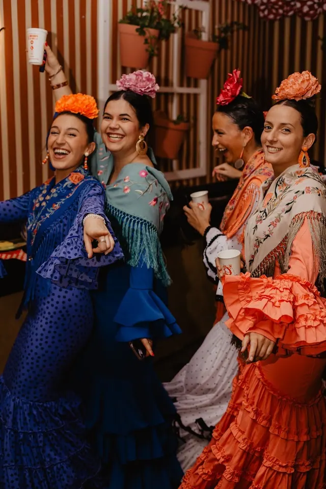 Mujeres con trajes de flamenca de colores bailando en la caseta